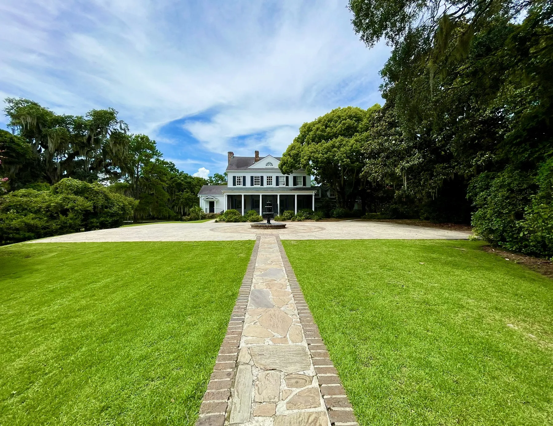 Freshly striped lawn and stone path leading to a white home
